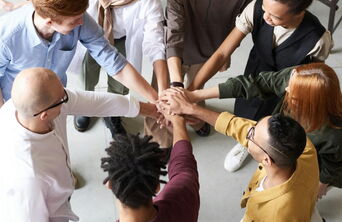 Hände-Stack eines Teams im Office als Symbol für starke Zusammenarbeit, Zusammenhalt und Motivation in der Webagentur 5150media.