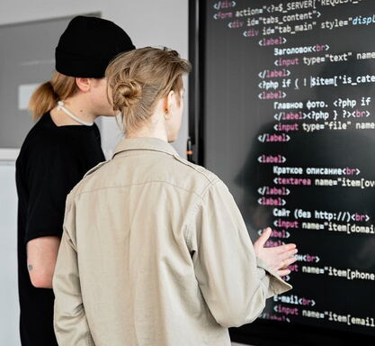 Zwei professionelle Webentwickler der Internetagentur 5150media prüfen und programmieren sauberen HTML5-Quellcode auf einem großen Monitor zur Optimierung einer Kundenwebseite