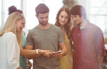 Zwei Business-Executives im modernen Büro bei einer Besprechung, während sie gemeinsam auf ein digitales Tablet schauen.